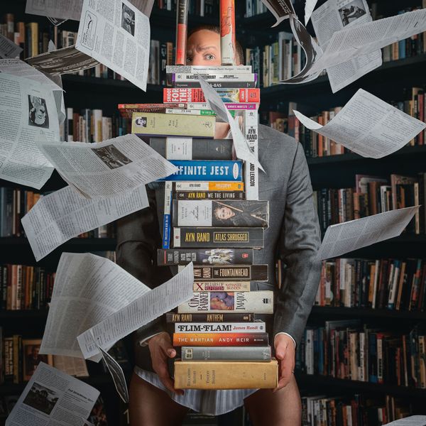 Person holding large stack of books