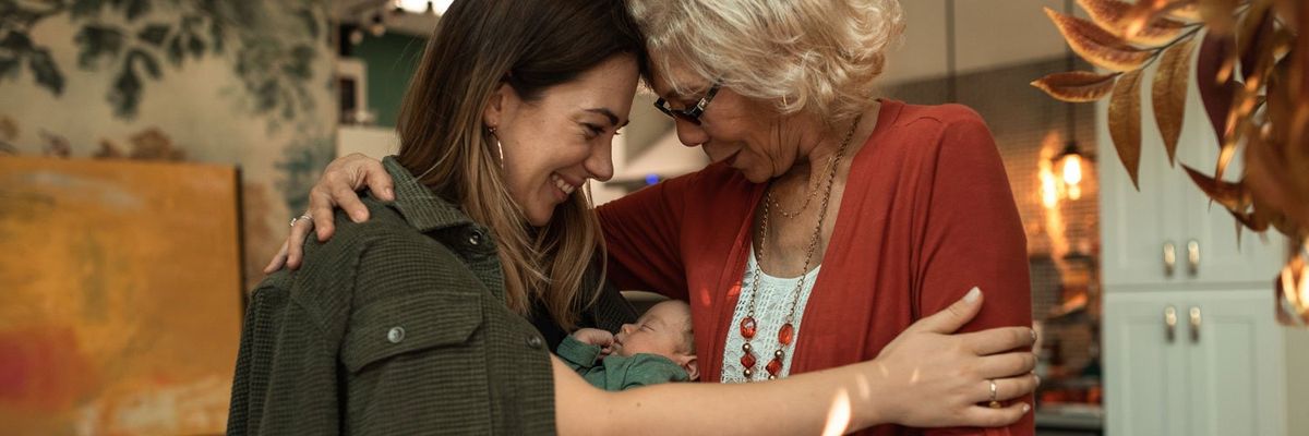 young woman with a baby in her arms hugs older woman