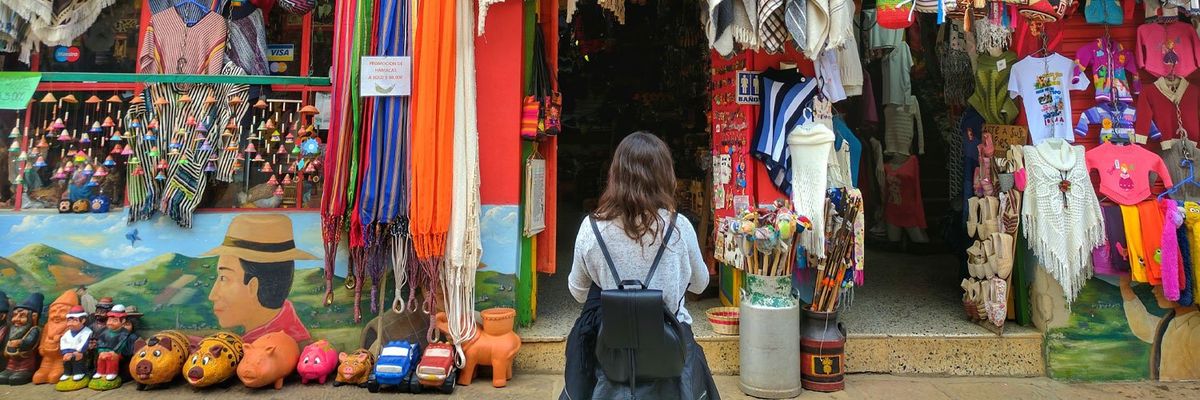 A young woman standing in front of a popular and colorful store featuring Latin American crafts