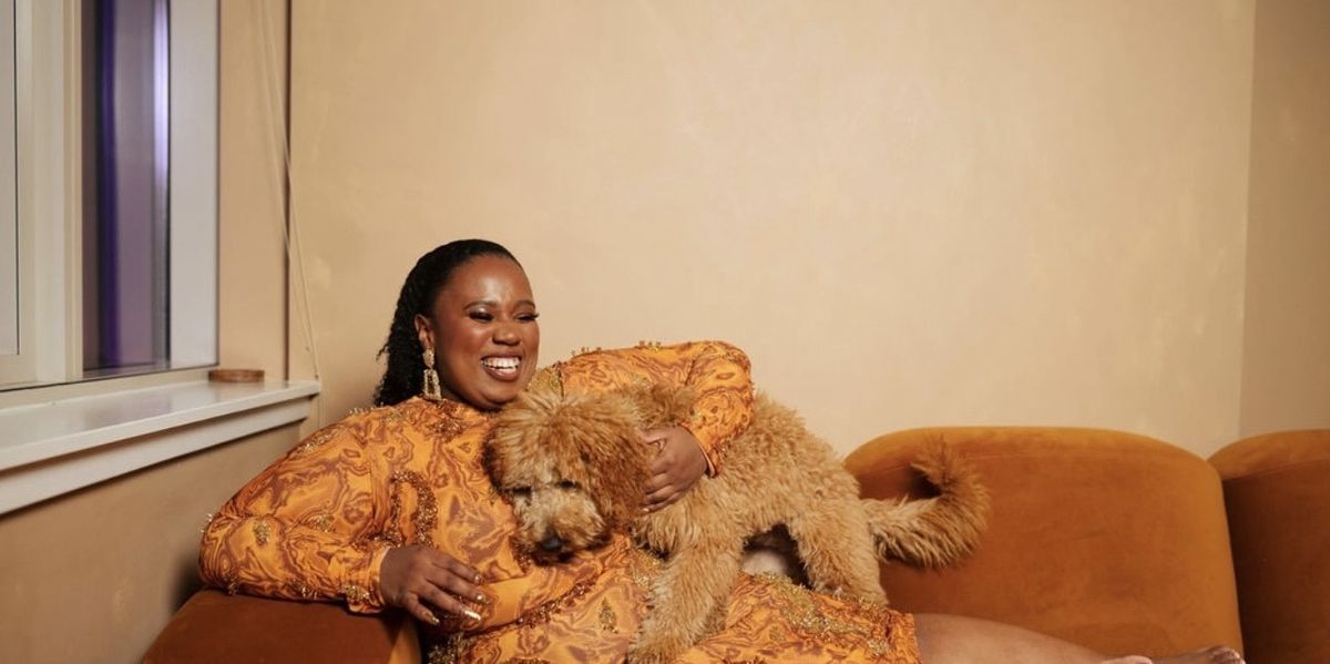 Black-woman-laughing-joyfully-whlie-relaxing-on-her-couch-playing-with-her-dog