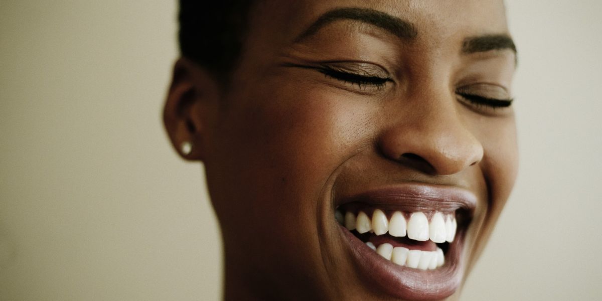 Black-woman-grinning-with-her-eyes-closed-showing-brilliant-white-smile