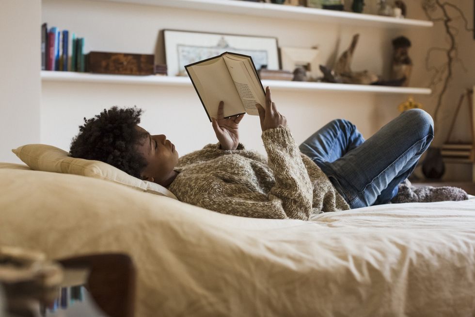 Black-woman-with-afro-hairstyle-relaxing-in-bed-reading-a-book