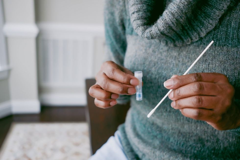 A-close-up-of-a-cotton-swab-testing-kit-being-held-in-a-woman-s-hands