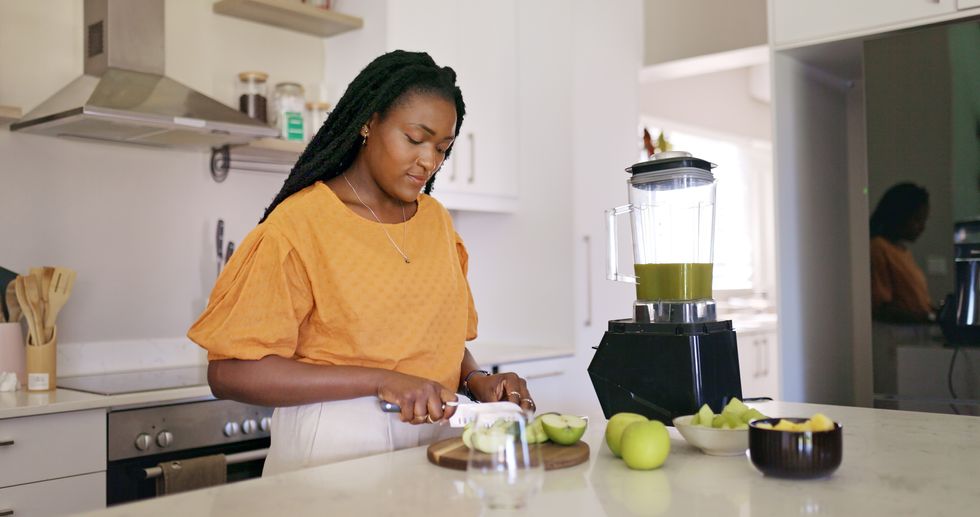 Black-woman-slicing-apples-in-her-kitchen-preparing-a-healthy-juice-at-home