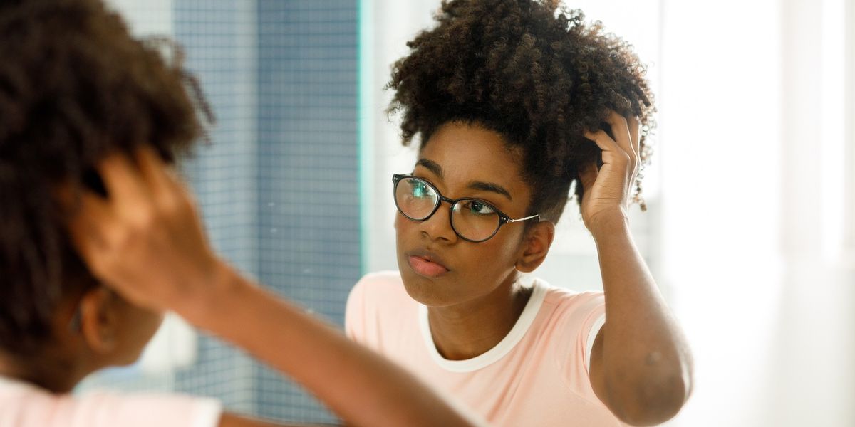 Black-woman-wearing-glasses-examining-her-Afro-in-the-mirror