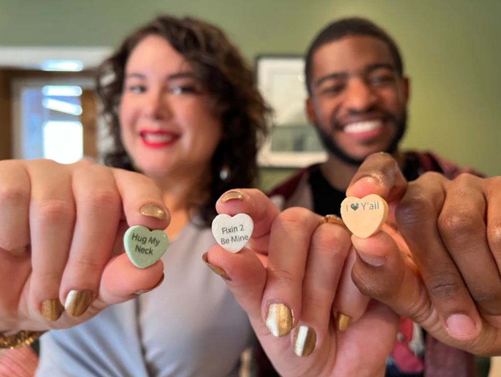 A woman and man hold up heart-shaped candies.