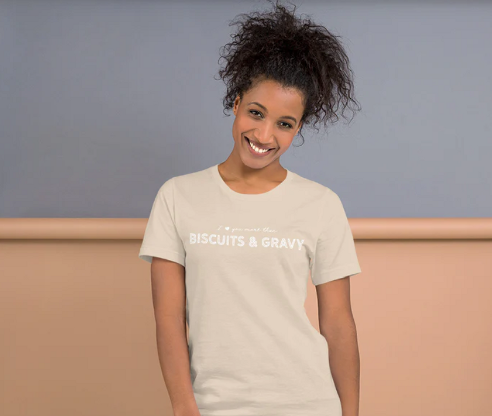 A woman wearing a beige T-shirts that says "I love you more than biscuits and gravy".