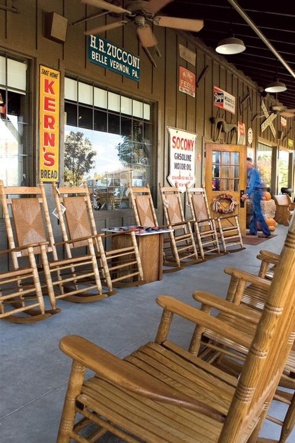 Several brown, wood rocking chairs lined up on the front porch of a Cracker Barrel restaurant.