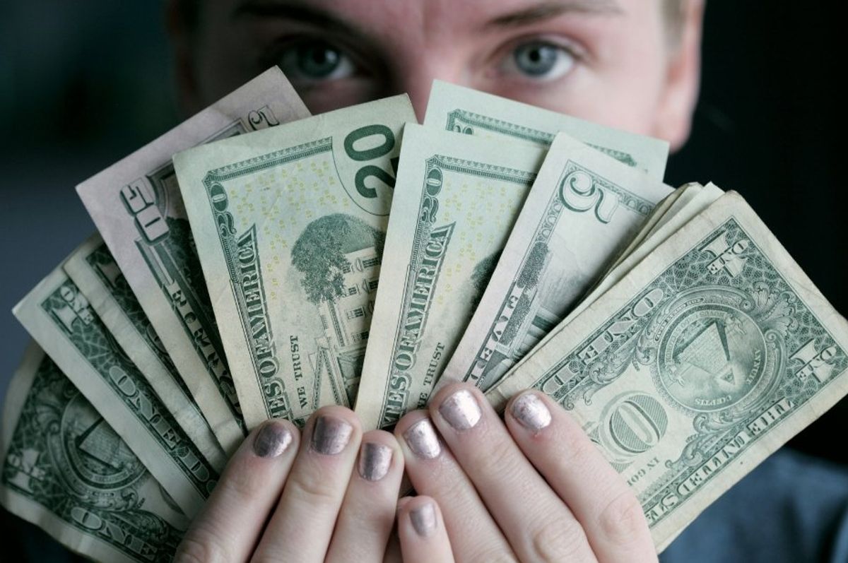 woman holding a bunch of cash bills fanned out