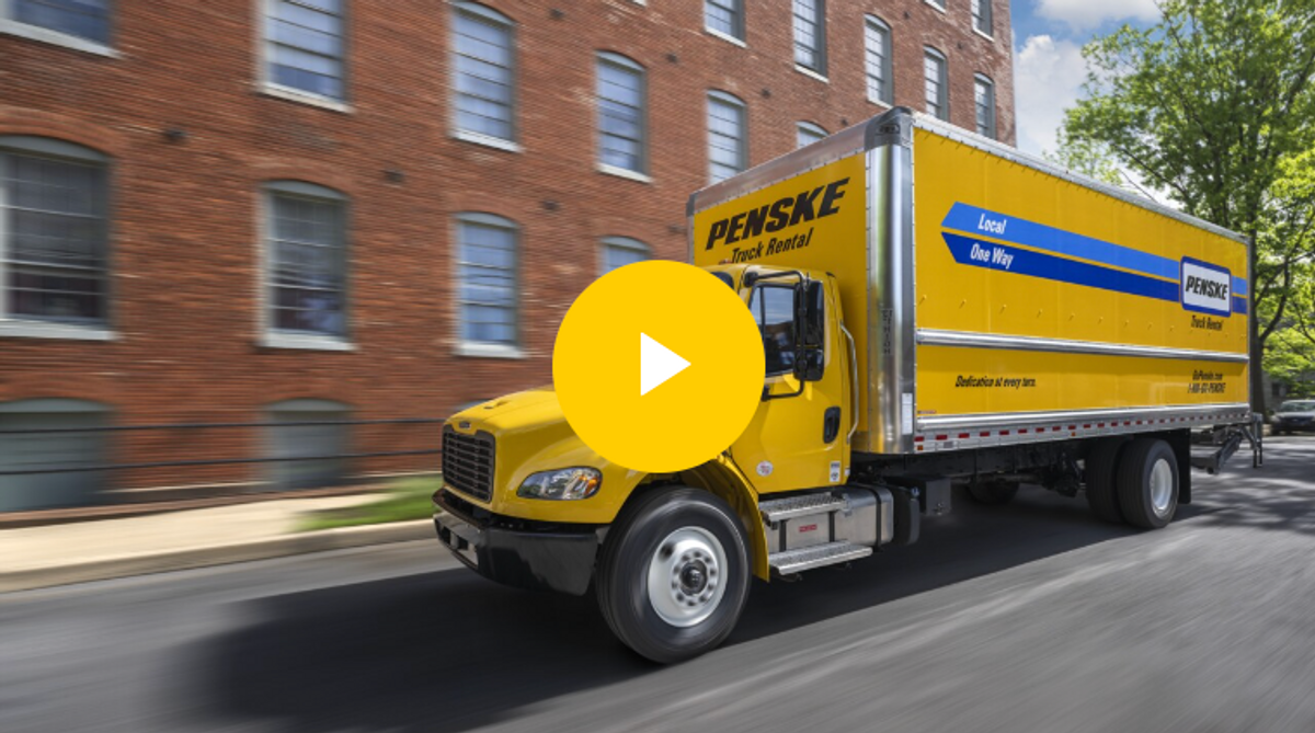 A yellow 22 to 26 foot Penske box truck driving on the road, linked to the truck video.