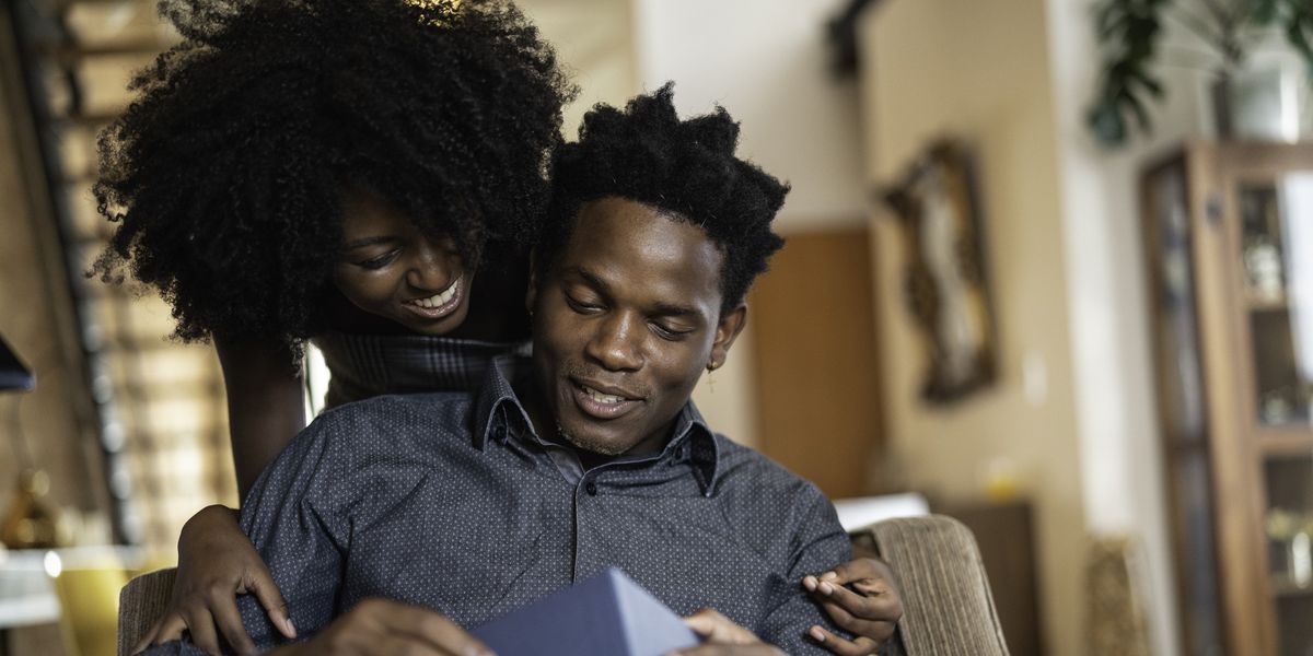 Black-couple-smiling-as-he-opens-his-gift