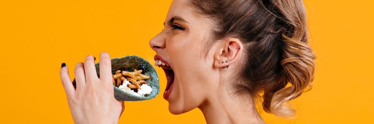 A woman about to take a bite of a taco filled with grasshoppers