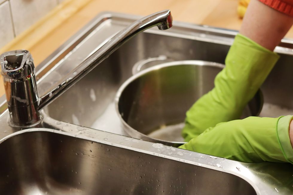 someone scrubbing a pot in a kitchen sink