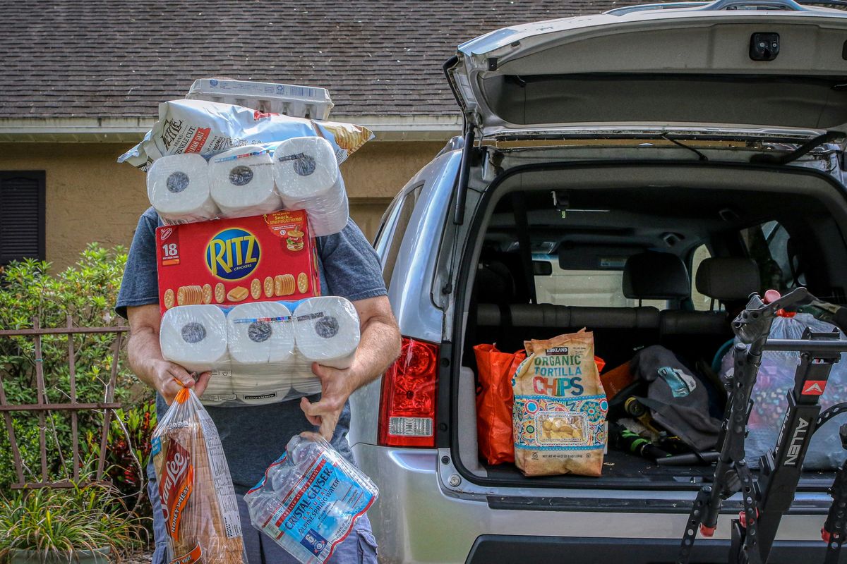 man pulling food and toilet paper out of the car