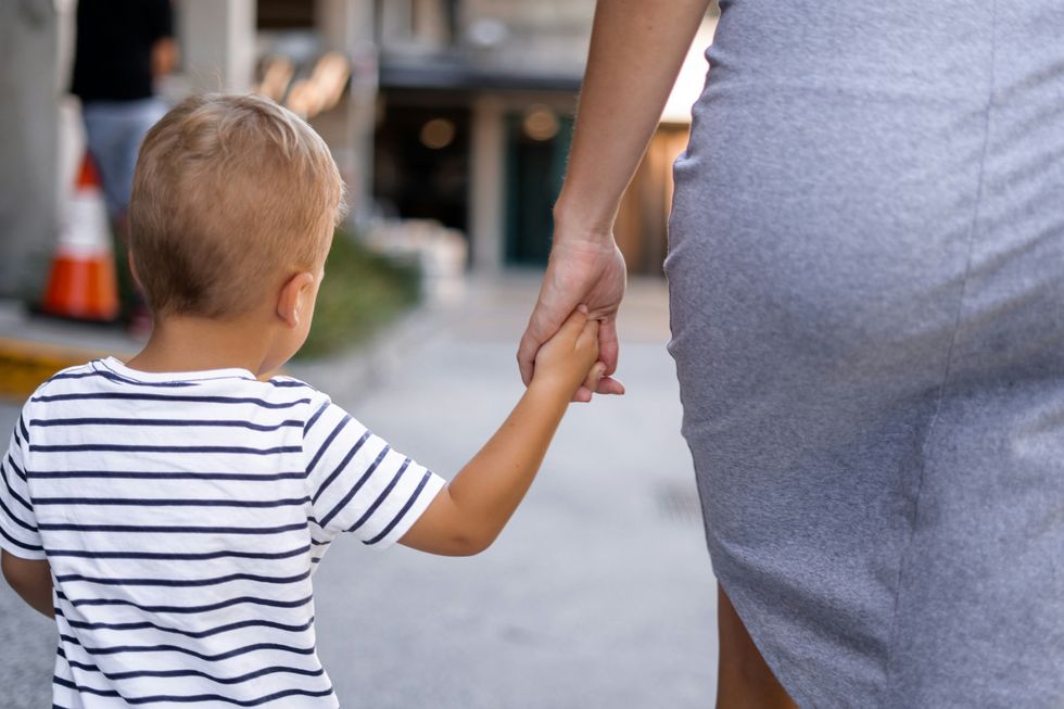 woman holding hands with a small child as they walk