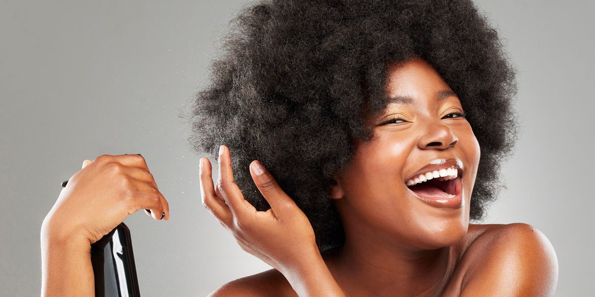 Happy-Black-woman-spraying-her-afro-with-bond-building-treatment