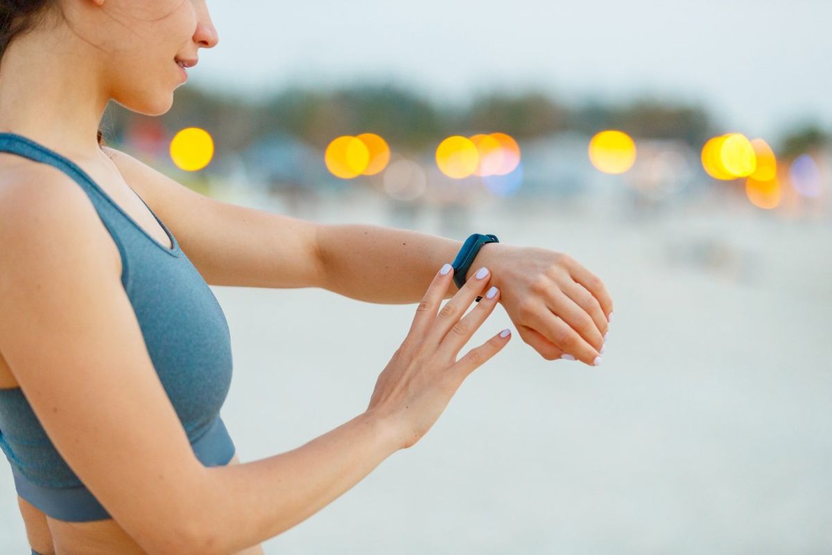 a woman wearing a fitness tracker and checking out her stats