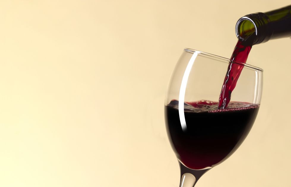 A-glass-of-red-wine-being-poured-in-front-of-yellow-background