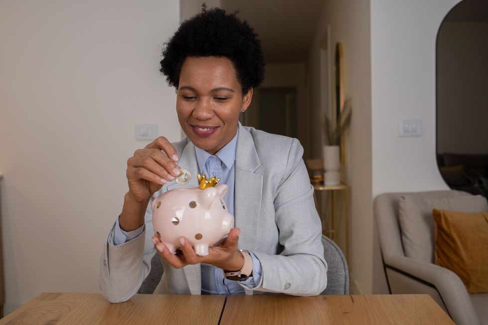 Woman-adding-coins-to-piggy-bank