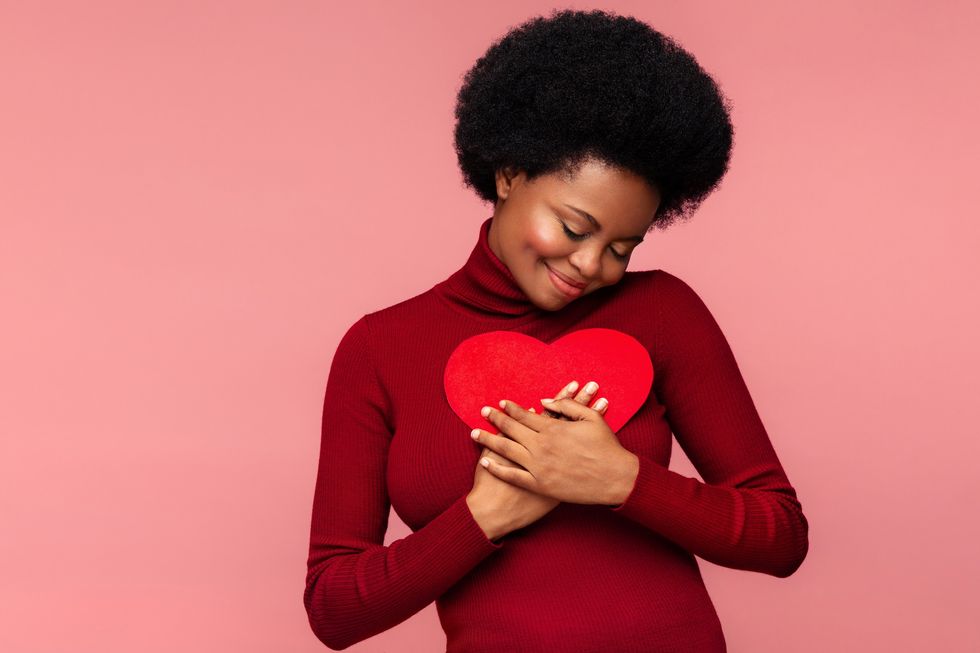 Black-woman-with-her-eyes-closed-holding-her-hands-over-her-heart-and-a-heart-cut-out-made-of-felt