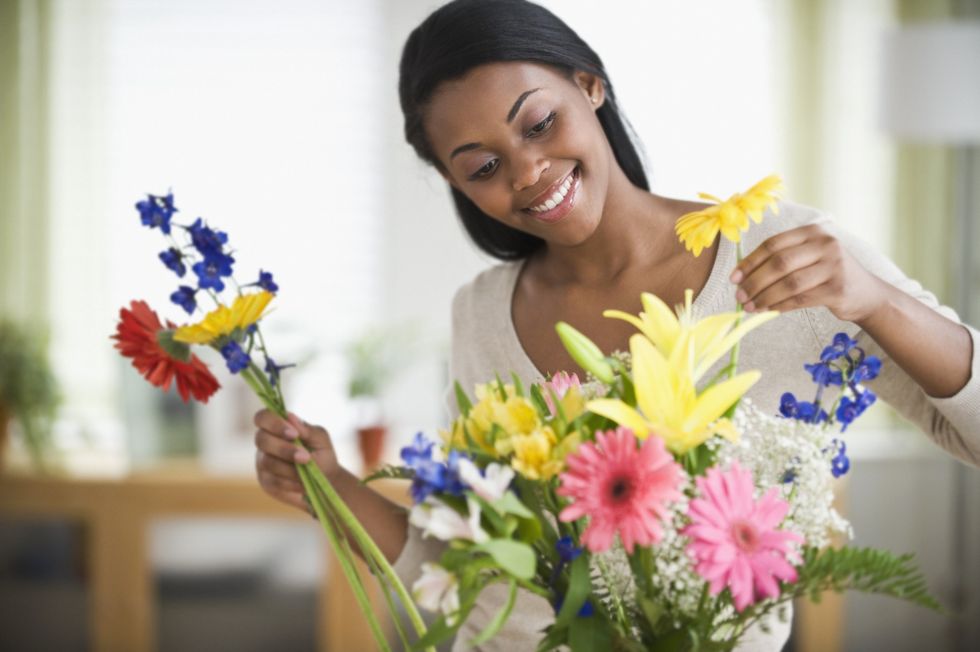 Smiling-Black-woman-arranging-her-own-flower-bouquet-at-home