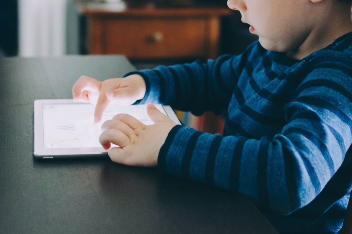 young child at a table with an ipad