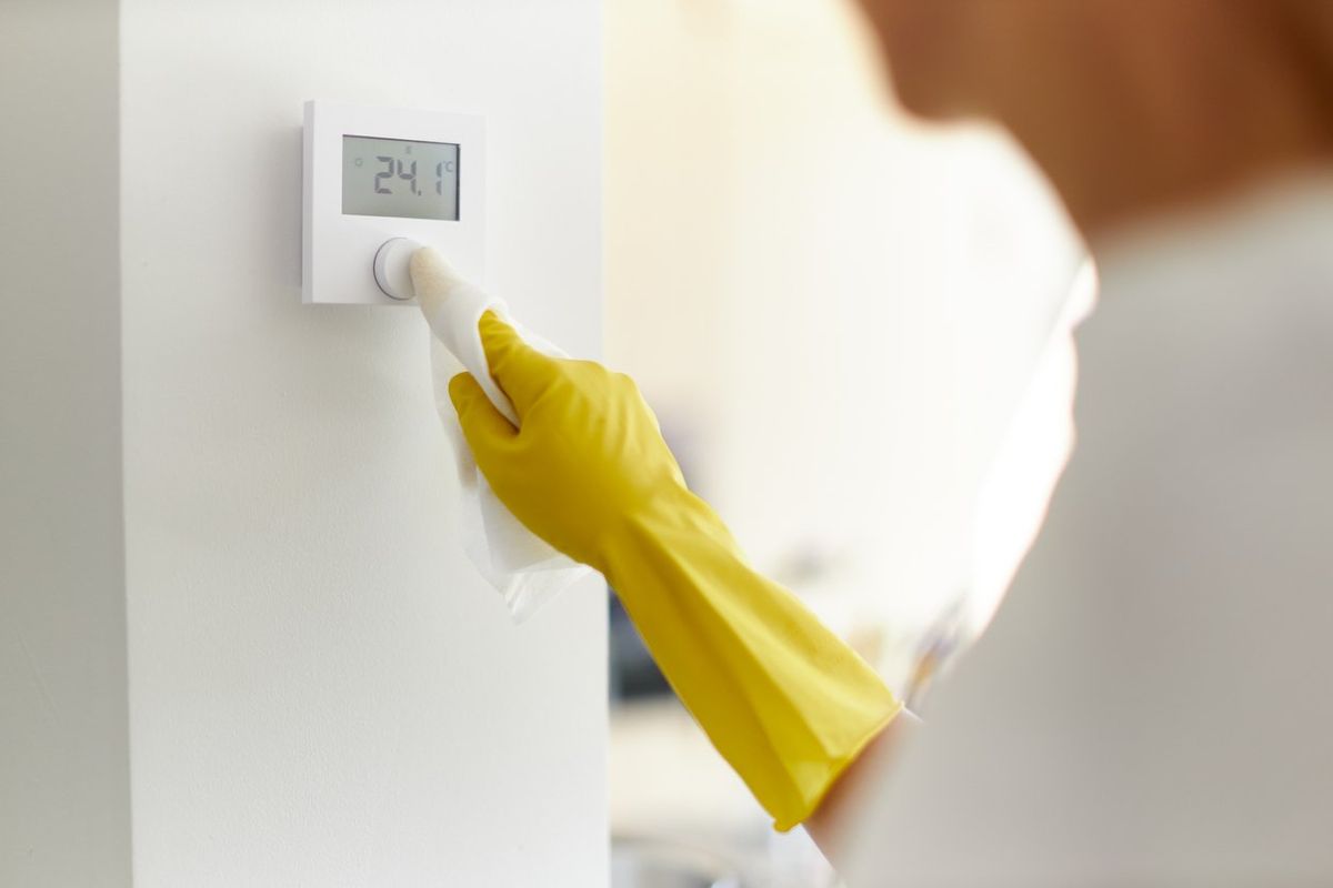 a photo of a woman cleaning a smart thermostat