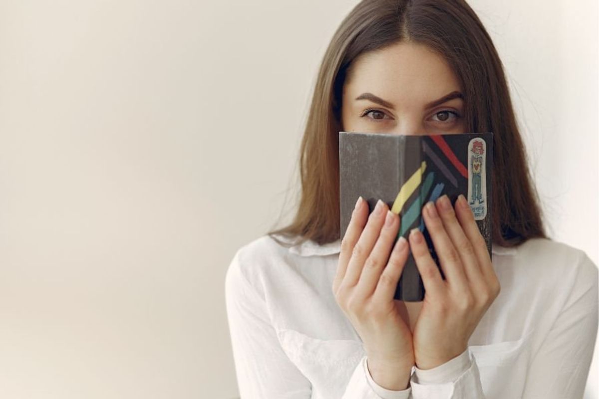 woman hiding her mouth with a book