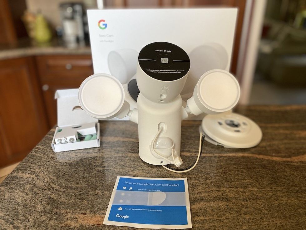 a photo of Google Nest Cam with Floodlight (Wired) unboxed on a counter.