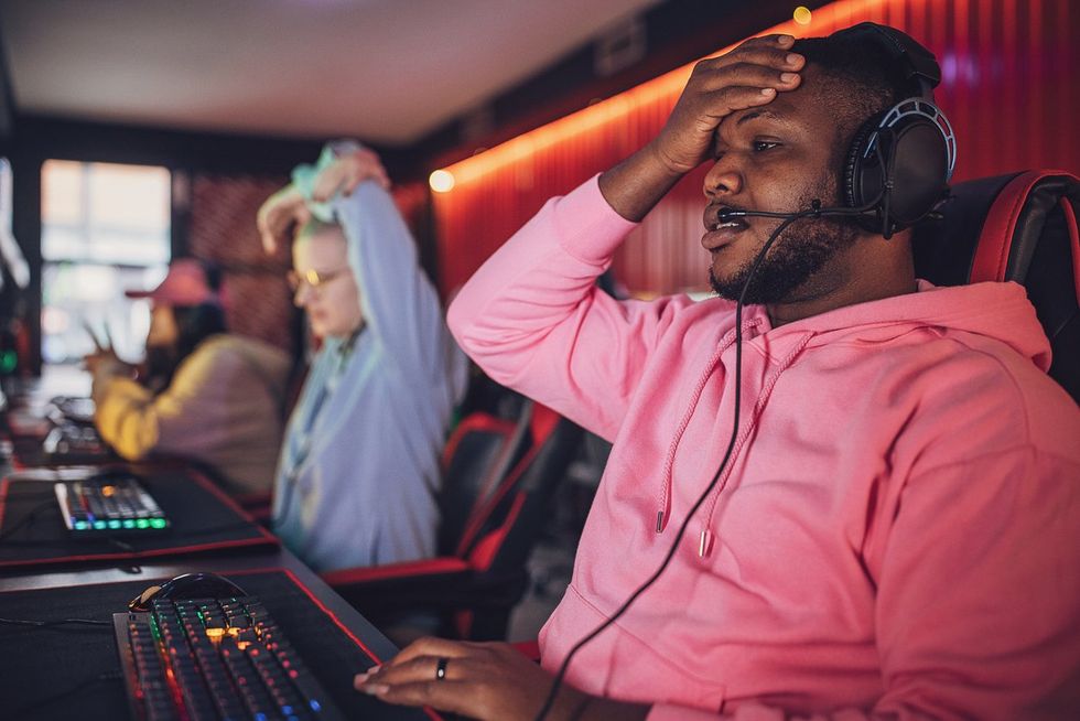 a photo of a black man playing online games and is frustrated.
