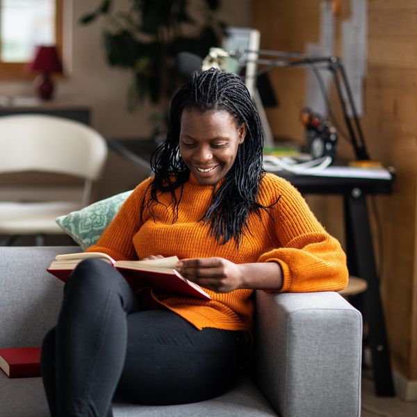 Cheerful-woman-turning-pages-of-her-book-reading-on-the-couch