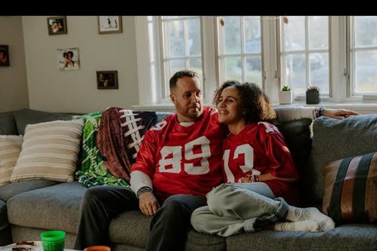 dad and daughter in football jerseys snuggled up on the sofa