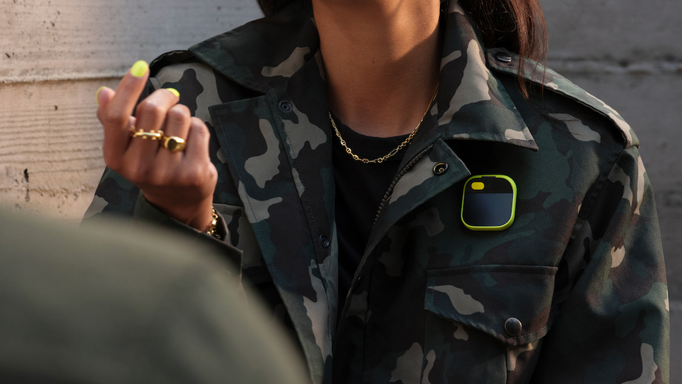 a photo of a woman wearing a Humane AI Pin on her jacket