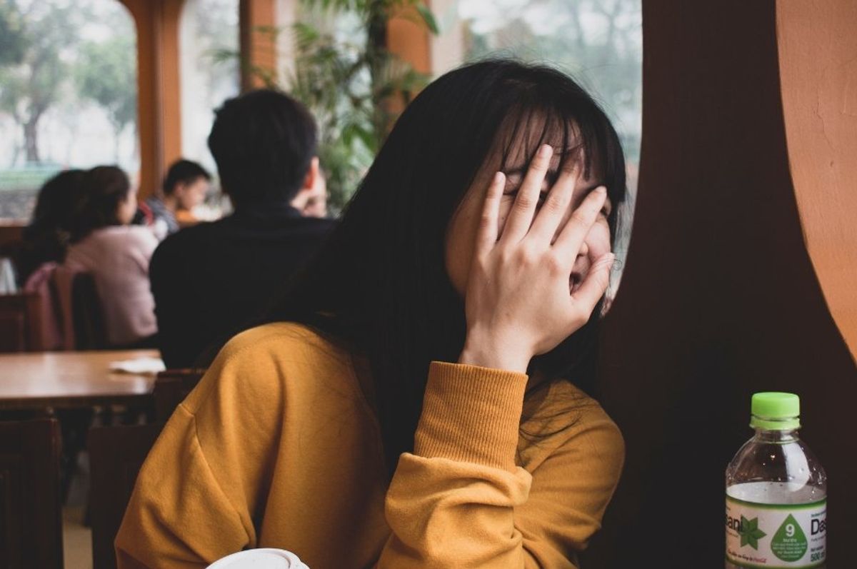 woman in a restaurant covering her face with her hand
