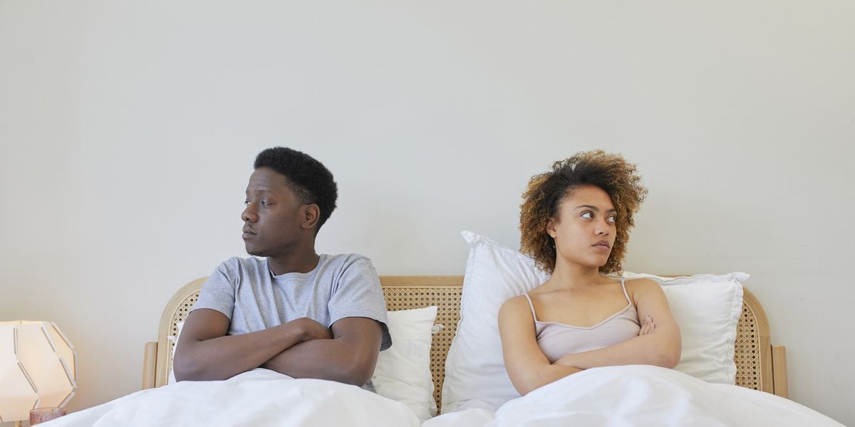 Young-couple-in-bed-next-to-each-other-looking-away-from-each-other-looking-irritated