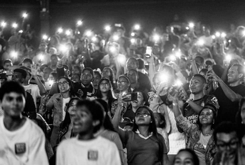 A diverse crowd of Latinos, all engrossed in the same focal point, recording and photographing the moment with their cell phones.