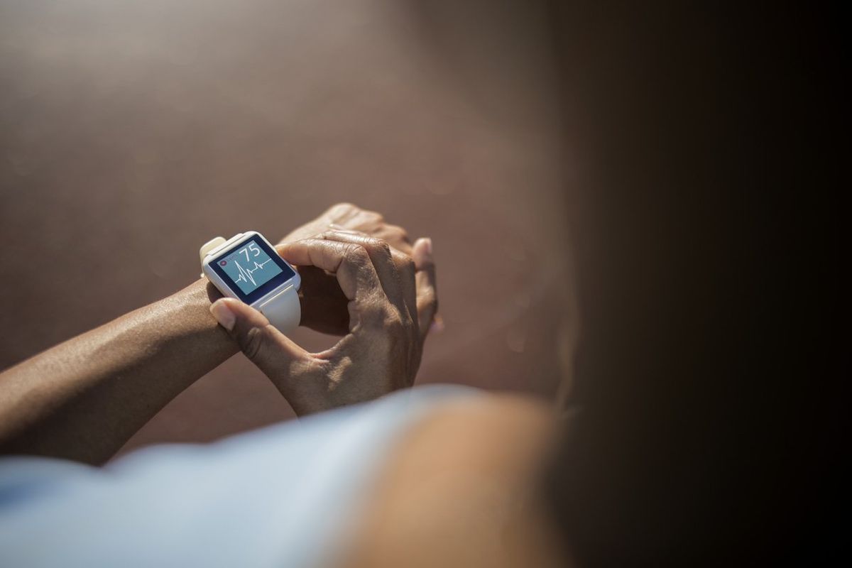 a photo of a woman taking her heart rate on a smartwatch