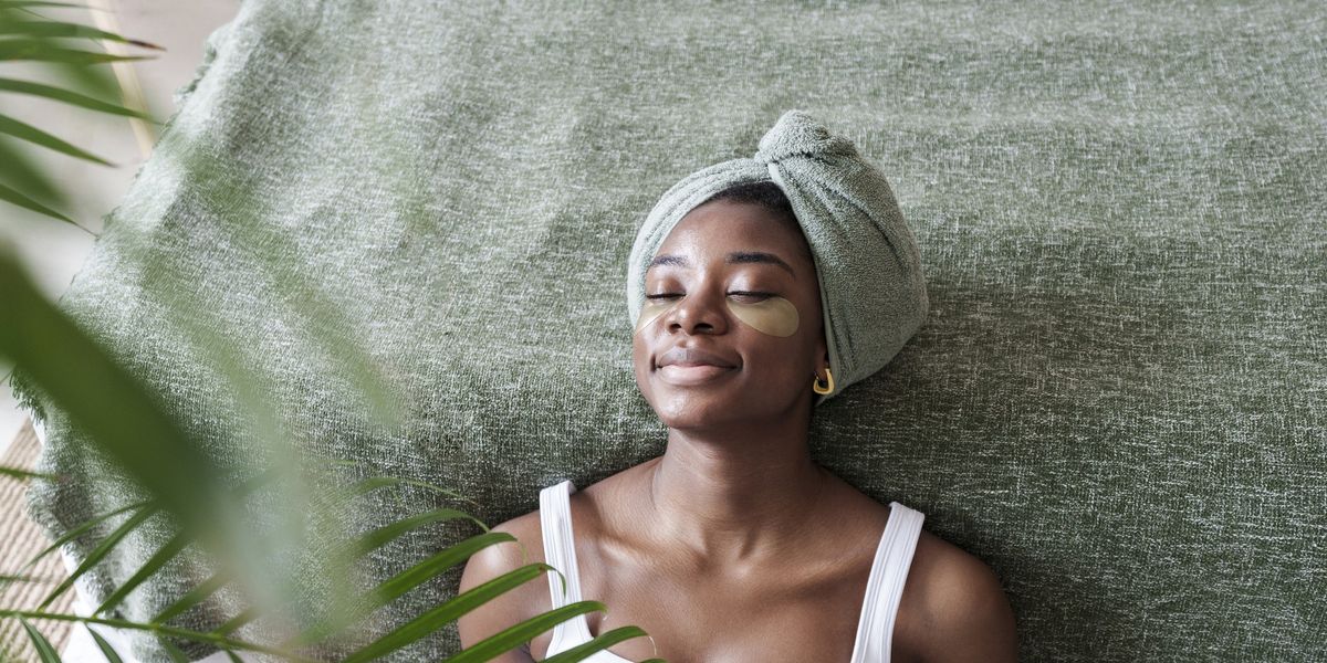 Black-woman-doing-skincare-treatment-at-home-leaning-against-bed