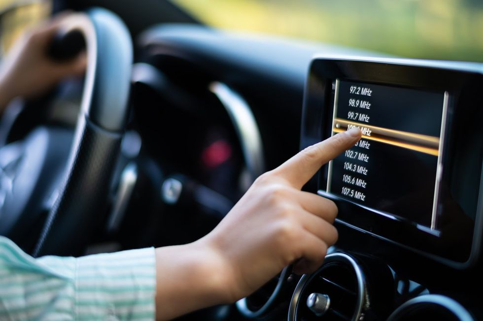 a person touching the screen on their car stereo.