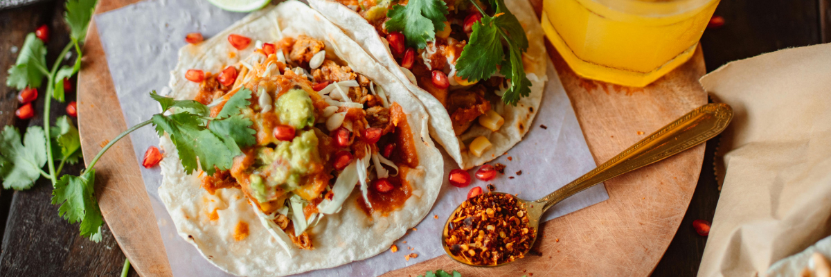 photograph of a colorful table full of fresh ingredients and 2 tacos ready to eat