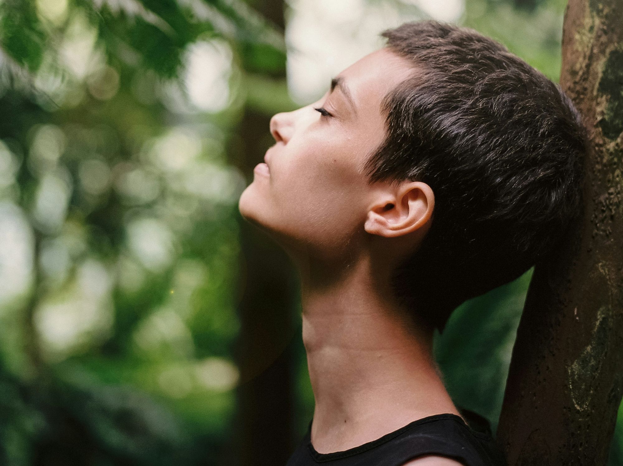 Woman leaning back on tree and breathing