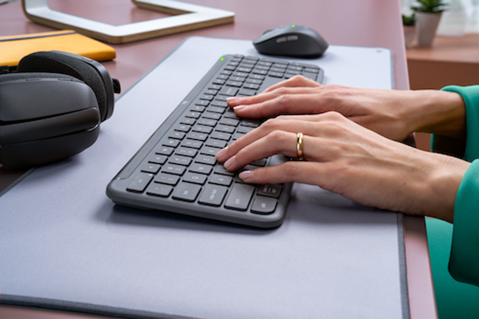 a photo of a woman's hands typing on the ignature Slim MK950 Wireless Keyboard