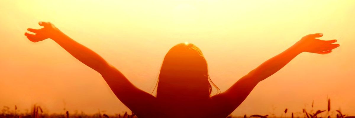 A woman extending her arms to the sky during sunset
