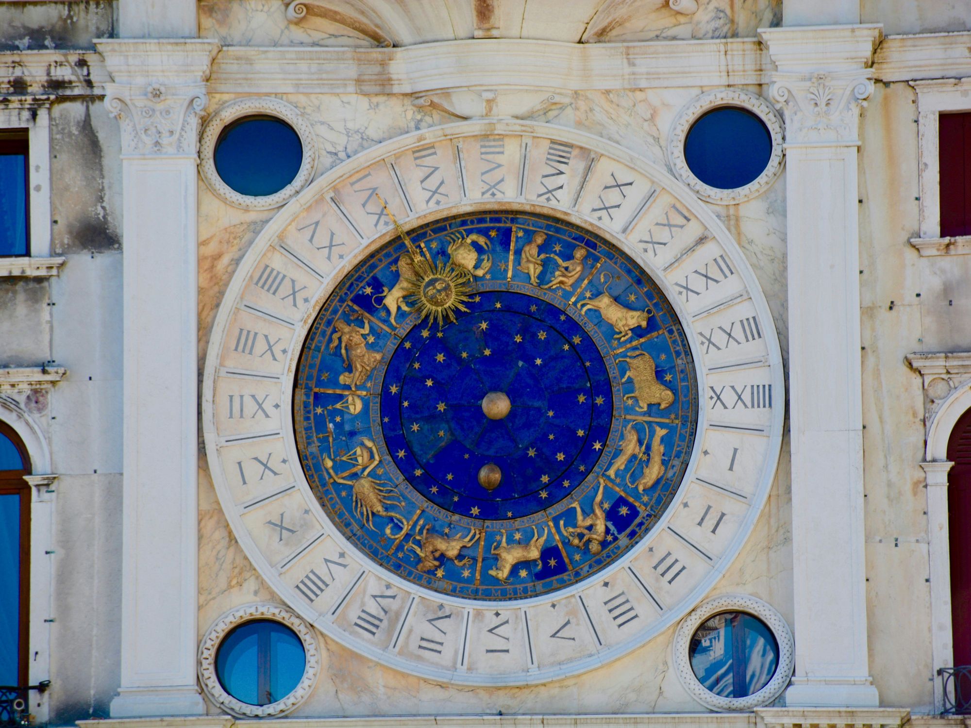 Sculpture on building facade showing zodiac clock with signs and astrological houses.