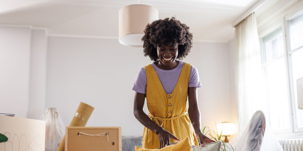 A-cheerful-Black-woman-with-a-big-smile-unpacking-moving-boxes-in-her-new-home