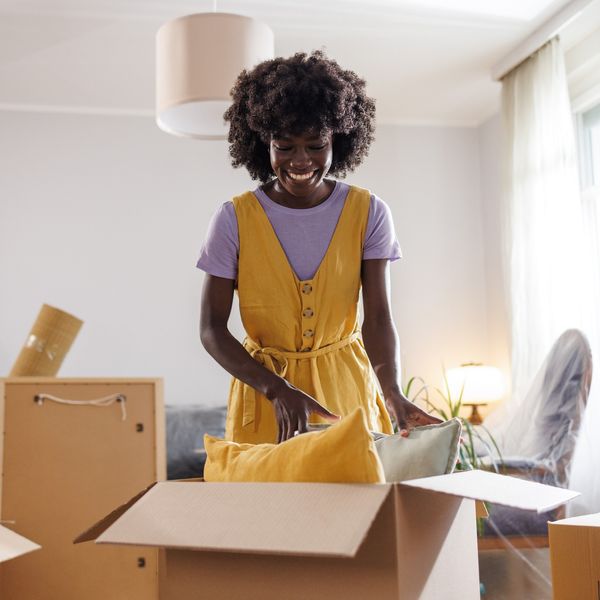 A-cheerful-Black-woman-with-a-big-smile-unpacking-moving-boxes-in-her-new-home