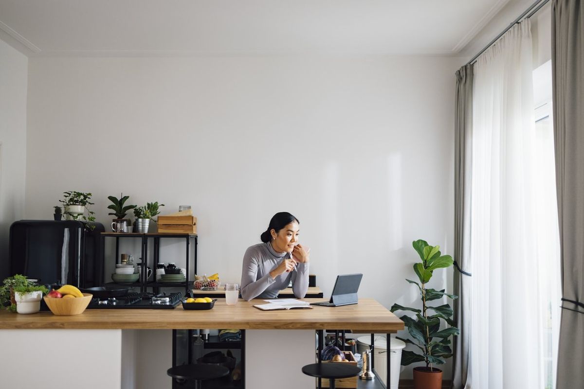 a photo of a woman sitting behind a desk on her laptop in her home office.