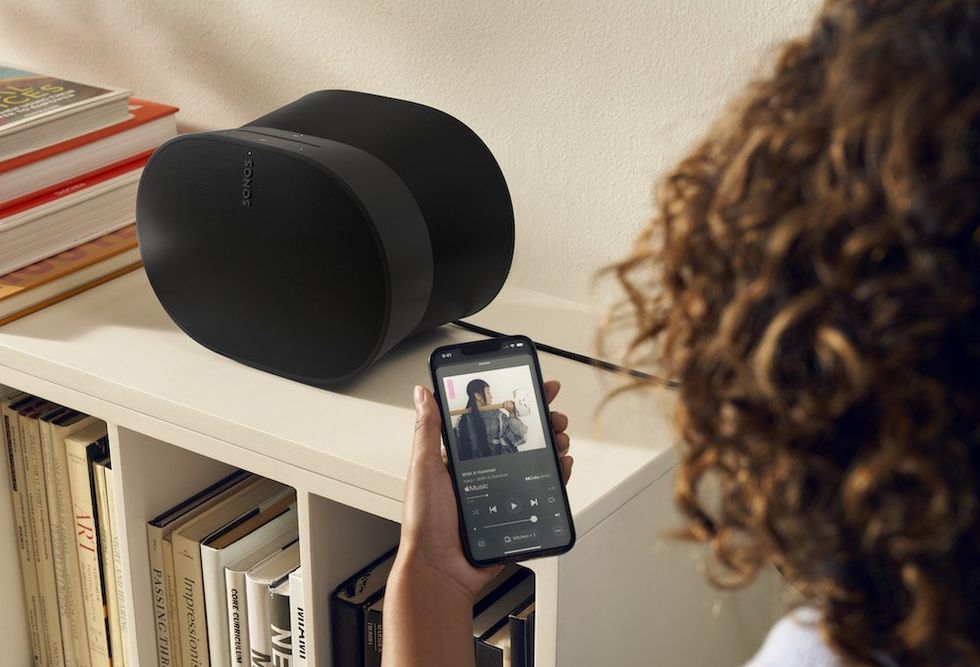 a woman on her smartphone with Sonos app open controlling music playing on Sonos Era 300 speaker.