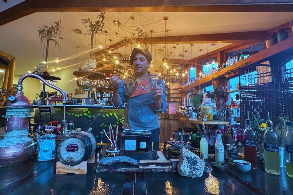 bartender standing in front of a table full of drink-making materials.