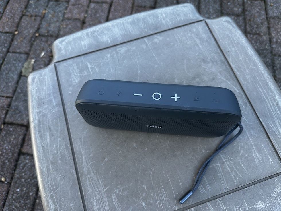 Photo of top of Tribit StormBox Flow Portable Wireless Speaker outside on a table.